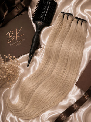 Hair extensions and a hairbrush on satin fabric with 'BK Beauty Kulture London' branding.